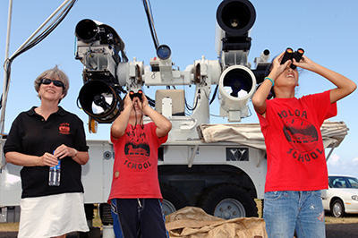 2 students looking at the sky through binoculars